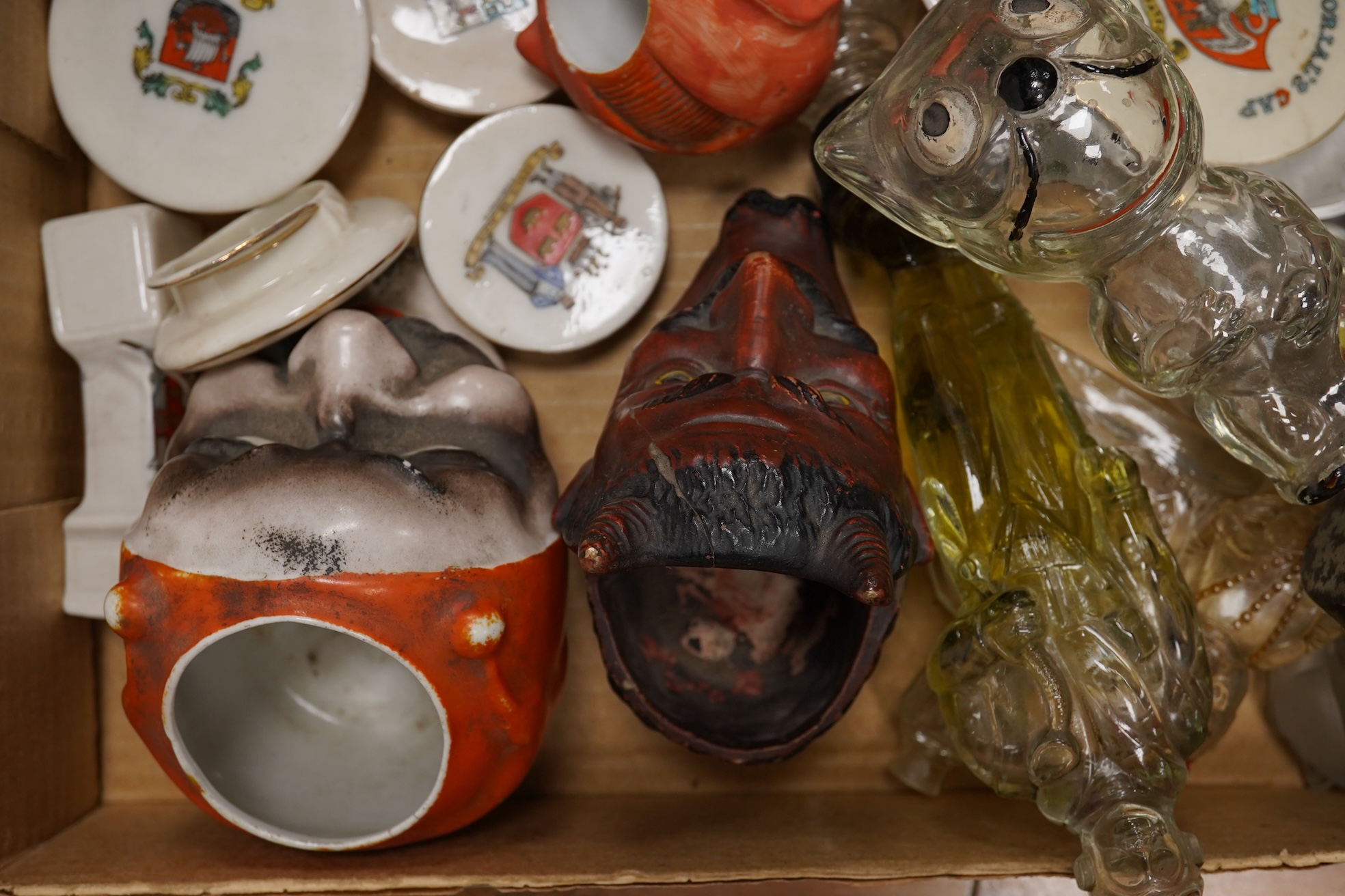 A collection of sundry items to include novelty glass bottles, devil pots and ceramic military caps